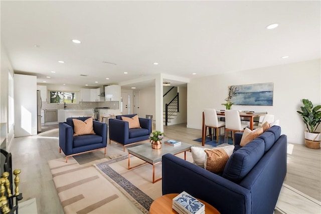 living area featuring recessed lighting, stairs, and light wood finished floors