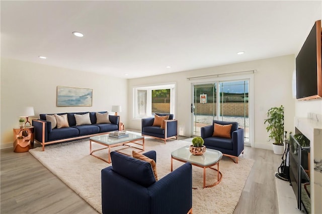 living room with recessed lighting, light wood-type flooring, baseboards, and a premium fireplace