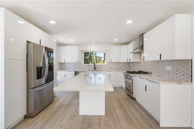 kitchen with tasteful backsplash, a kitchen island, stainless steel appliances, wall chimney exhaust hood, and a sink