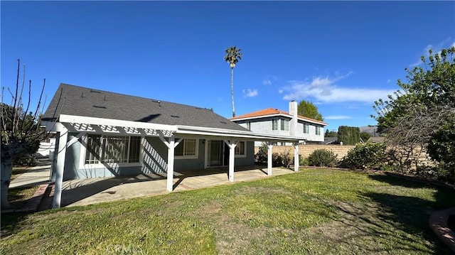 rear view of house featuring a patio, a lawn, and fence