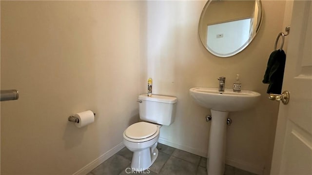 half bath featuring baseboards, toilet, and tile patterned flooring