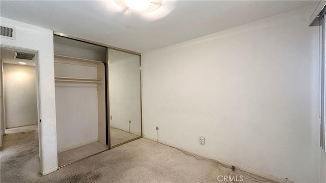 unfurnished bedroom with visible vents, carpet, and a closet