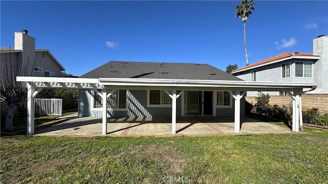 rear view of property featuring a patio area, stucco siding, a lawn, and fence