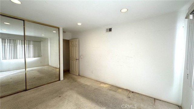 unfurnished bedroom with a closet, recessed lighting, visible vents, and carpet floors