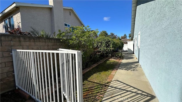 view of side of property with stucco siding and fence