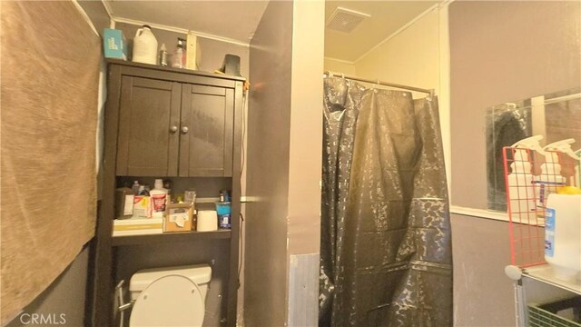 bathroom with toilet, a shower with shower curtain, and visible vents