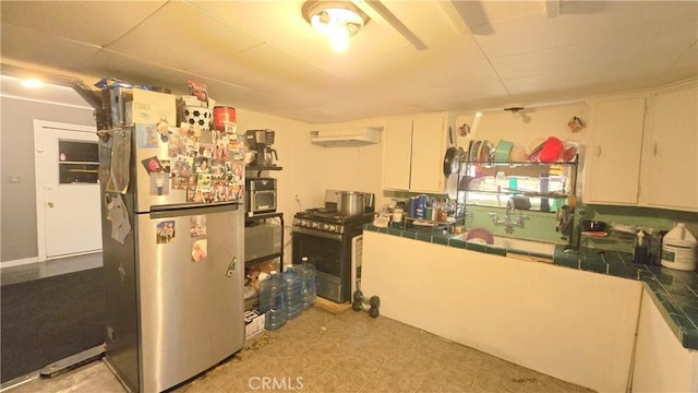 kitchen featuring stainless steel appliances, tile counters, white cabinets, and under cabinet range hood