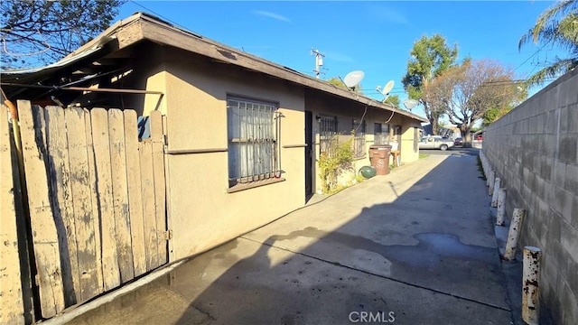 view of side of home featuring a patio area, fence, and stucco siding