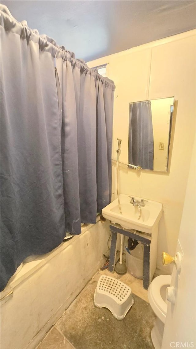 bathroom featuring a sink, shower / tub combo with curtain, and toilet