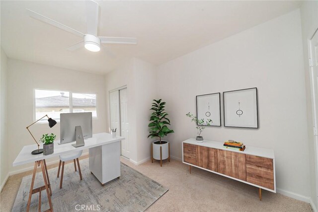 office featuring baseboards, a ceiling fan, and light colored carpet