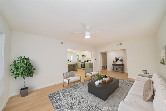 living area featuring light wood-type flooring, visible vents, ceiling fan, and baseboards