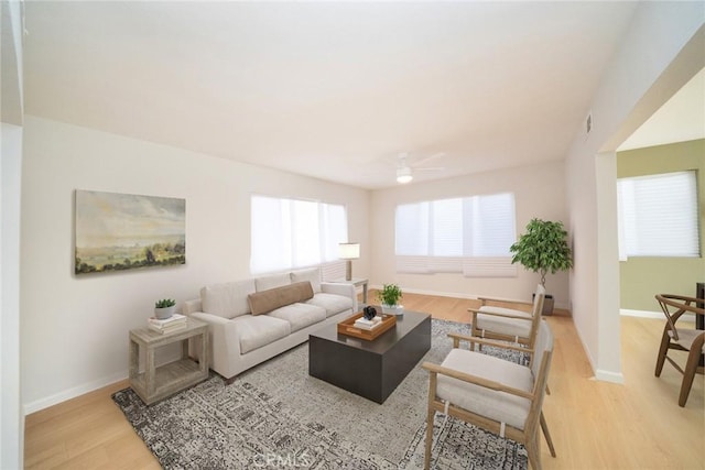 living room featuring ceiling fan, light wood finished floors, and baseboards