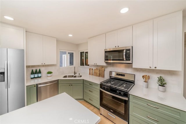 kitchen featuring a sink, white cabinets, light countertops, appliances with stainless steel finishes, and green cabinetry