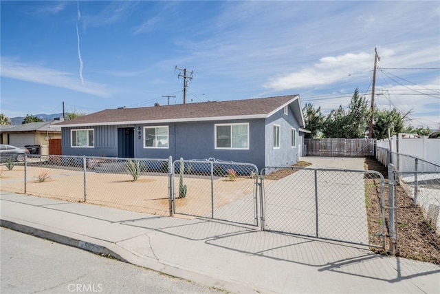 view of front of house with a fenced front yard, a gate, driveway, and stucco siding