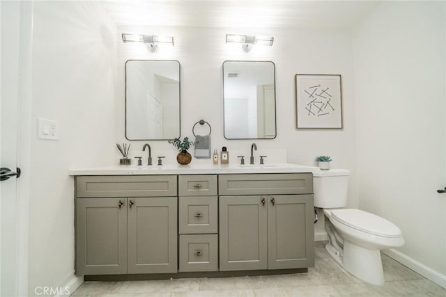 full bathroom featuring double vanity, a sink, toilet, and baseboards