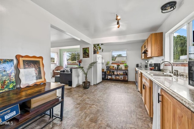 kitchen with brown cabinets, range with electric stovetop, freestanding refrigerator, a sink, and under cabinet range hood