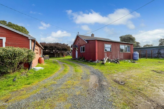 view of property exterior with driveway, fence, and a yard