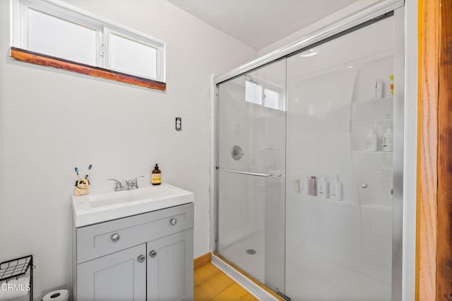 full bathroom featuring a shower stall, wood finished floors, and vanity