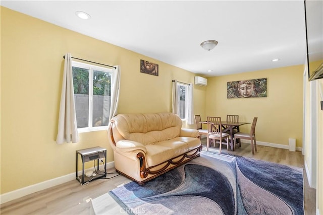 living room with light wood-style flooring, baseboards, an AC wall unit, and recessed lighting