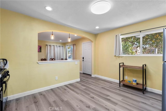 interior space featuring arched walkways, recessed lighting, baseboards, and wood finished floors