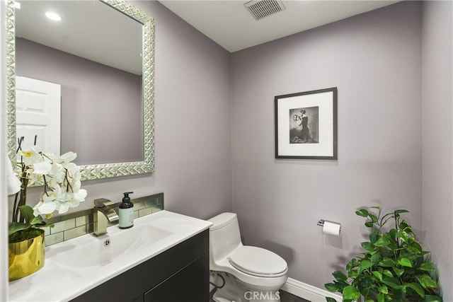 bathroom with toilet, baseboards, visible vents, and vanity