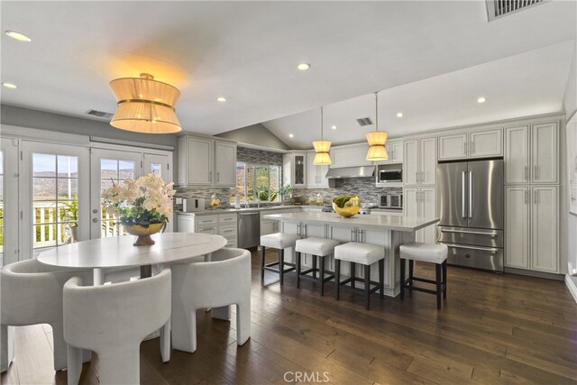 dining space with visible vents, vaulted ceiling, dark wood-type flooring, and french doors