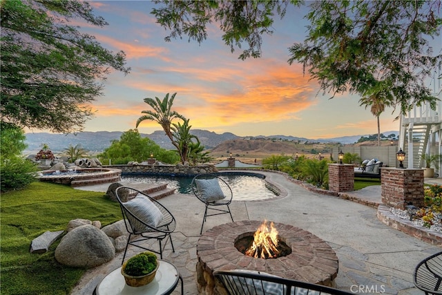 view of pool with an outdoor fire pit, a lawn, a patio area, and a mountain view