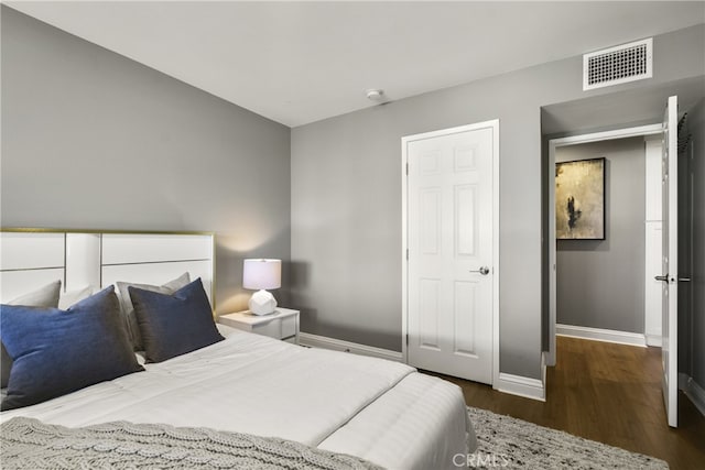 bedroom with wood finished floors, visible vents, and baseboards