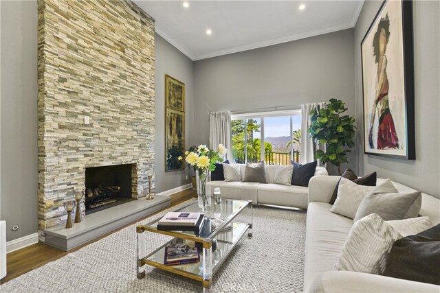 living area featuring ornamental molding, a fireplace, baseboards, and wood finished floors