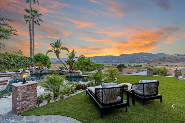 view of community featuring a mountain view, an outdoor living space, and a lawn