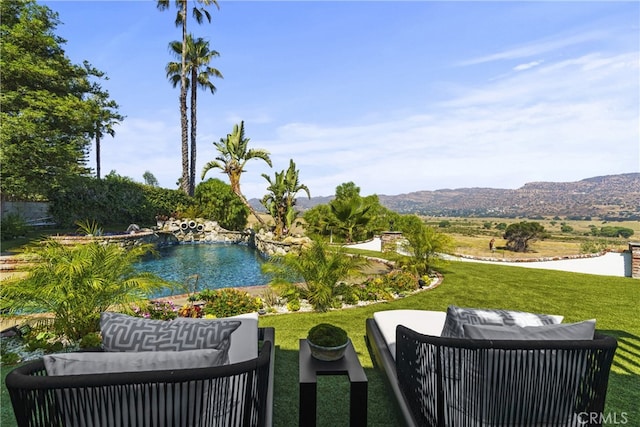 view of property's community featuring a lawn, an outdoor living space, and a mountain view