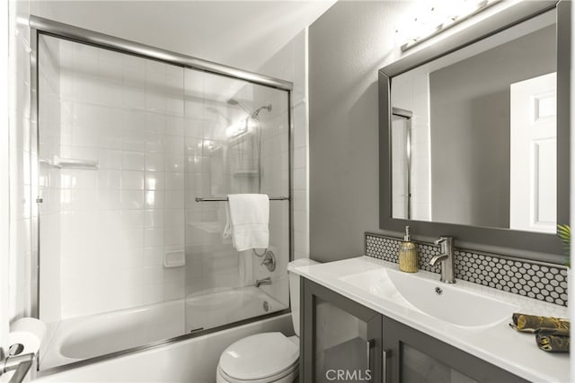 bathroom with combined bath / shower with glass door, vanity, and toilet