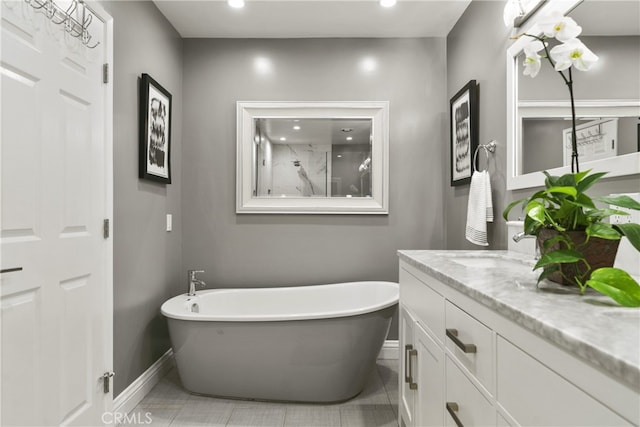 bathroom with recessed lighting, a freestanding bath, vanity, baseboards, and tile patterned floors