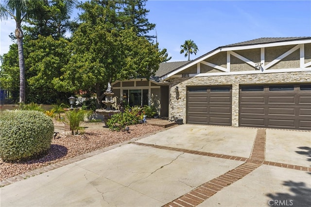 view of front of house with driveway, stone siding, and a garage