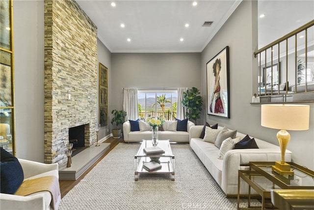 living area with crown molding, a fireplace, recessed lighting, visible vents, and wood finished floors