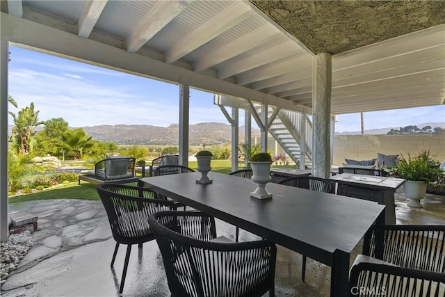 view of patio featuring stairway, fence, a mountain view, and outdoor dining space