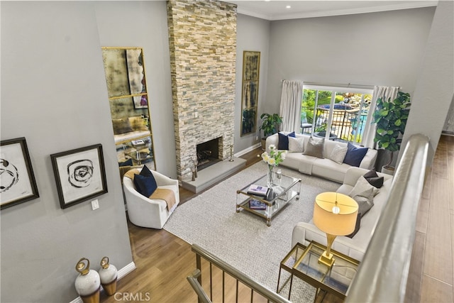 living room with baseboards, a fireplace, ornamental molding, and wood finished floors