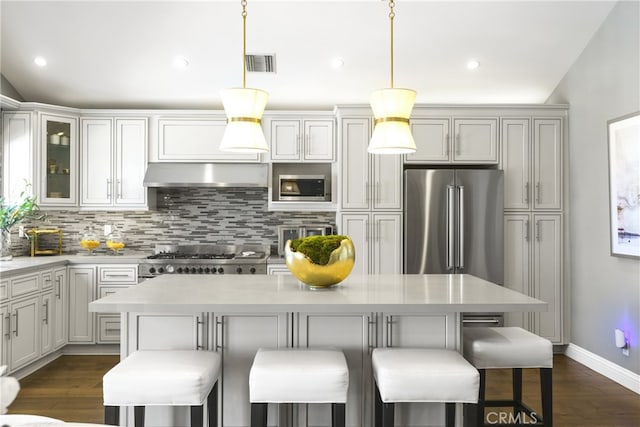 kitchen with visible vents, decorative backsplash, a center island, range hood, and stainless steel appliances