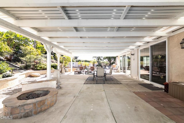 view of patio with outdoor dining space, fence, and a fire pit