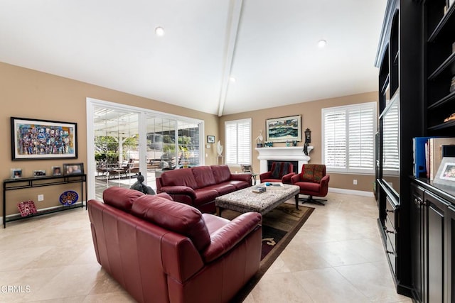 living area with vaulted ceiling, a glass covered fireplace, a wealth of natural light, and baseboards