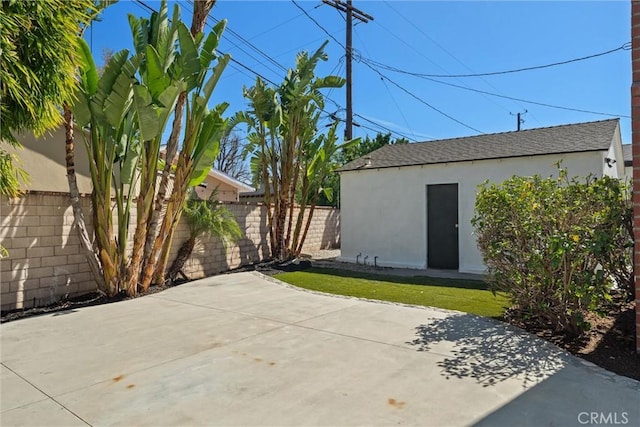 view of patio with an outbuilding and fence