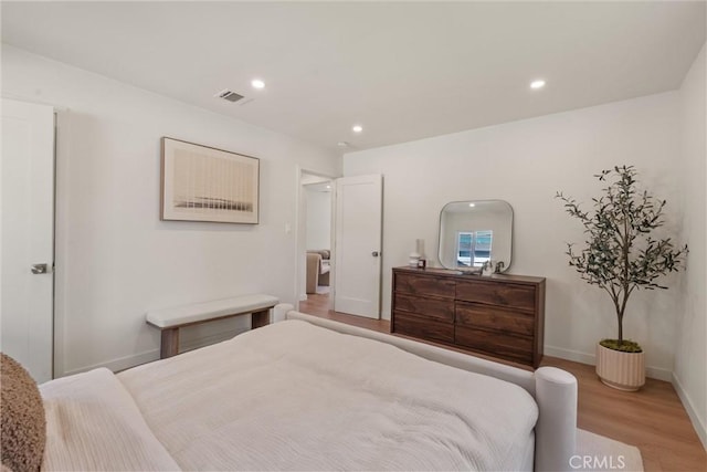 bedroom with baseboards, light wood finished floors, visible vents, and recessed lighting