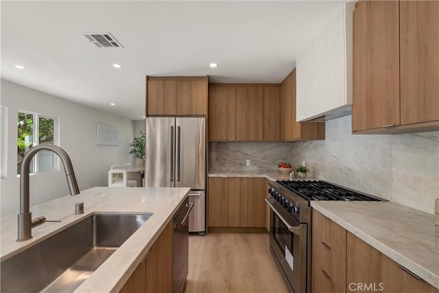 kitchen with stainless steel appliances, brown cabinets, a sink, and visible vents