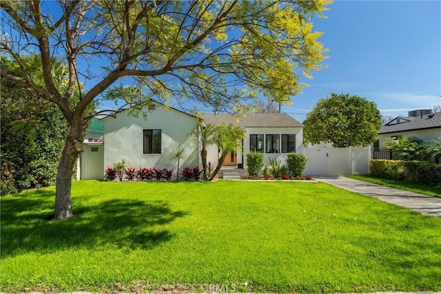 ranch-style home with stucco siding, a front yard, a gate, fence, and driveway