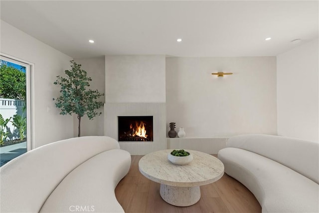 living area with recessed lighting, a fireplace, and wood finished floors