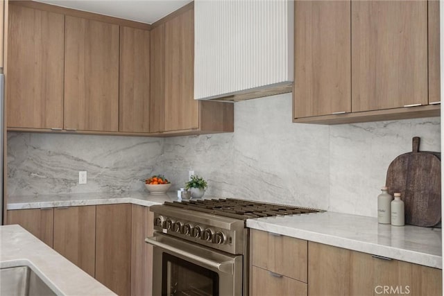 kitchen with light countertops, high end stainless steel range oven, decorative backsplash, and modern cabinets