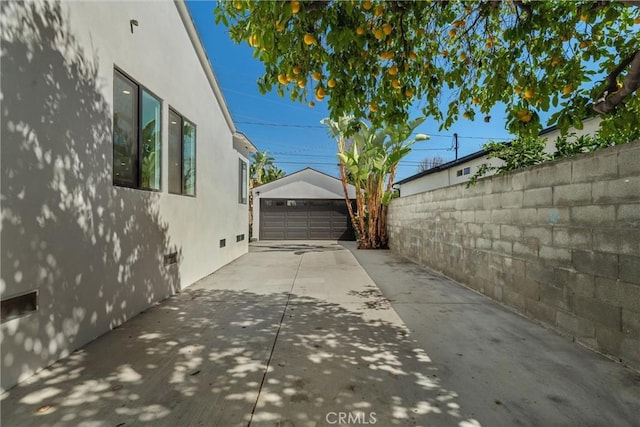 view of home's exterior with a patio, stucco siding, fence, a garage, and an outdoor structure