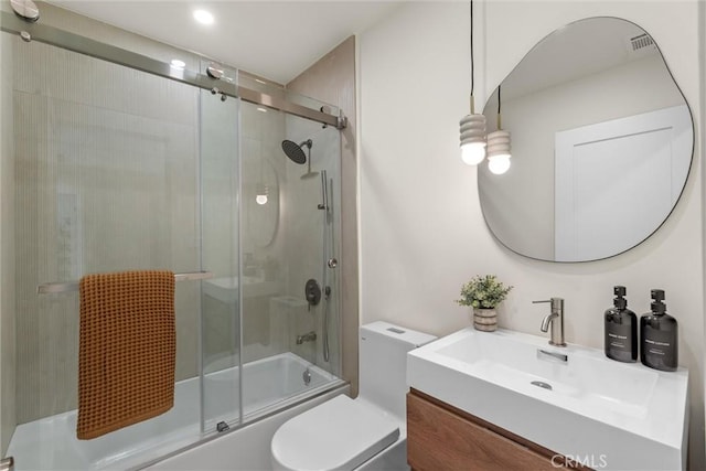 bathroom featuring combined bath / shower with glass door, vanity, and toilet