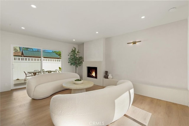 living room featuring recessed lighting, a lit fireplace, and wood finished floors