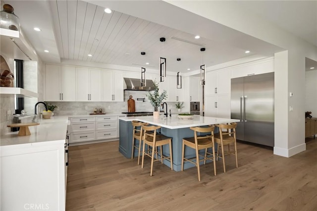 1820 9th St, Manhattan Beach, CA 90266 - kitchen featuring tasteful backsplash, built in fridge, under cabinet range hood, light wood finished floors, and a spacious island